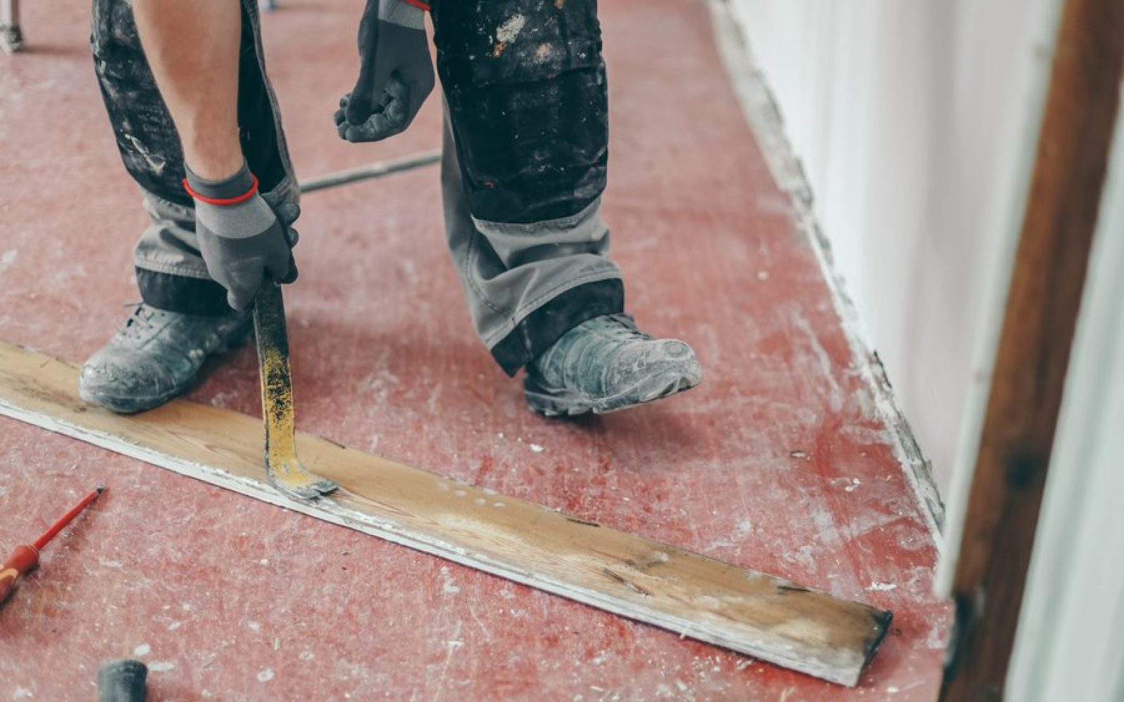The hands of a man pull out nails with a crowbar.